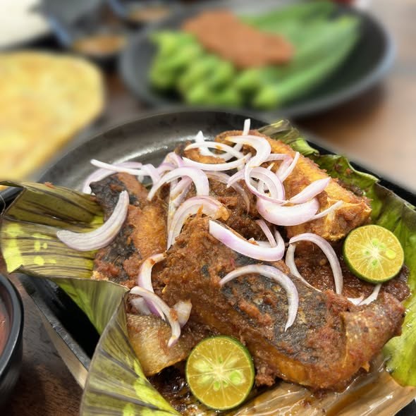 Grilled fish with sambal, onions and lime on a banana leaf