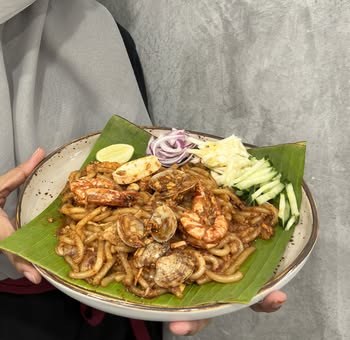 Fried laksa with prawns and clams on a banana leaf